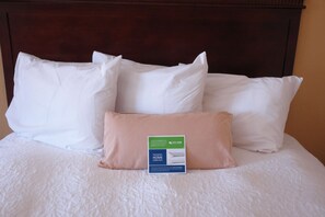 A neatly made bed with white and pink pillows and a Hampton Home Collection tag.