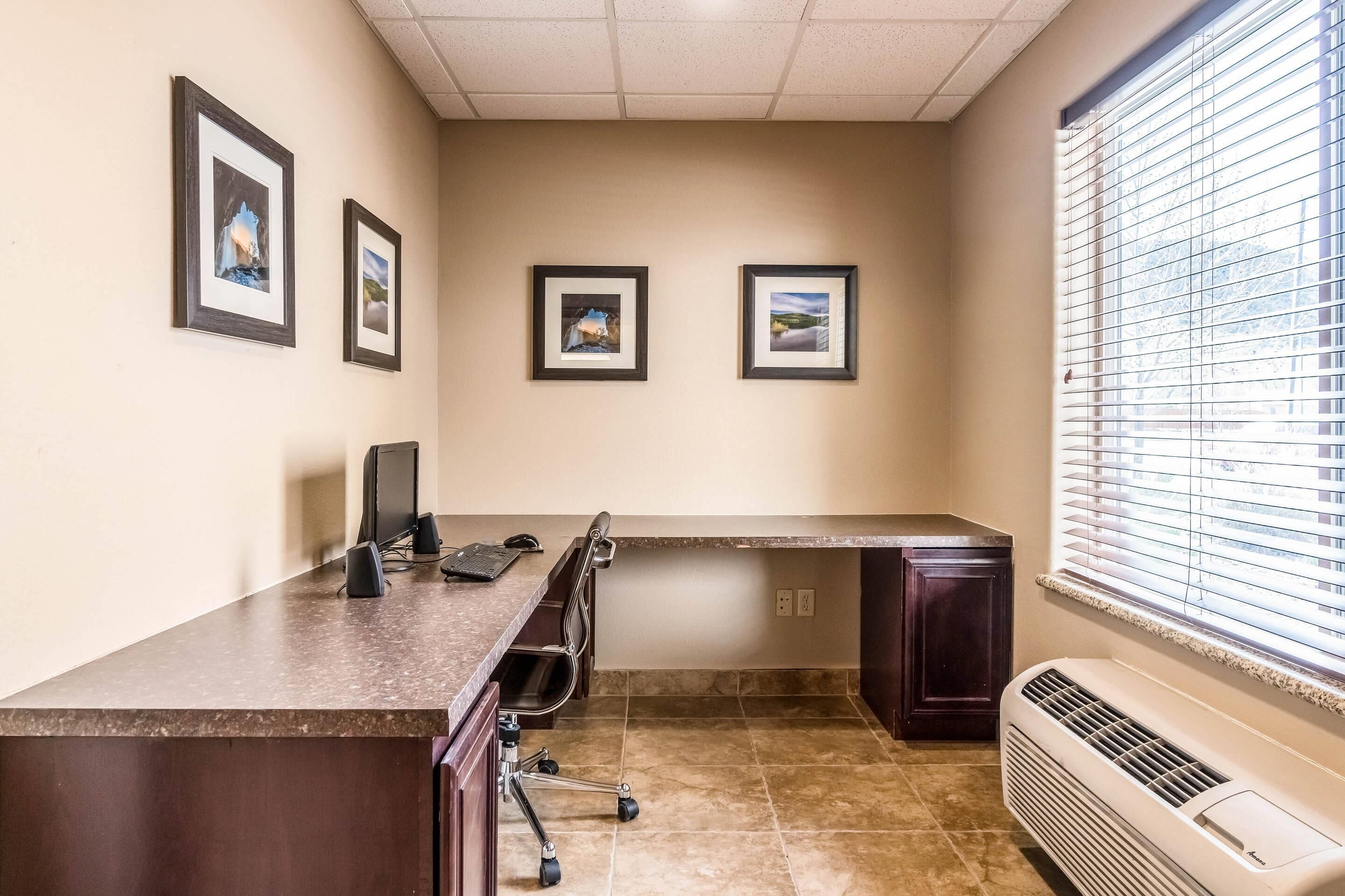 A conference room with a long table, chairs, framed pictures on the wall, and a window with blinds.