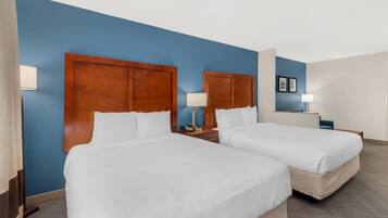 A hotel room with two beds, wooden headboards, and a blue accent wall.
