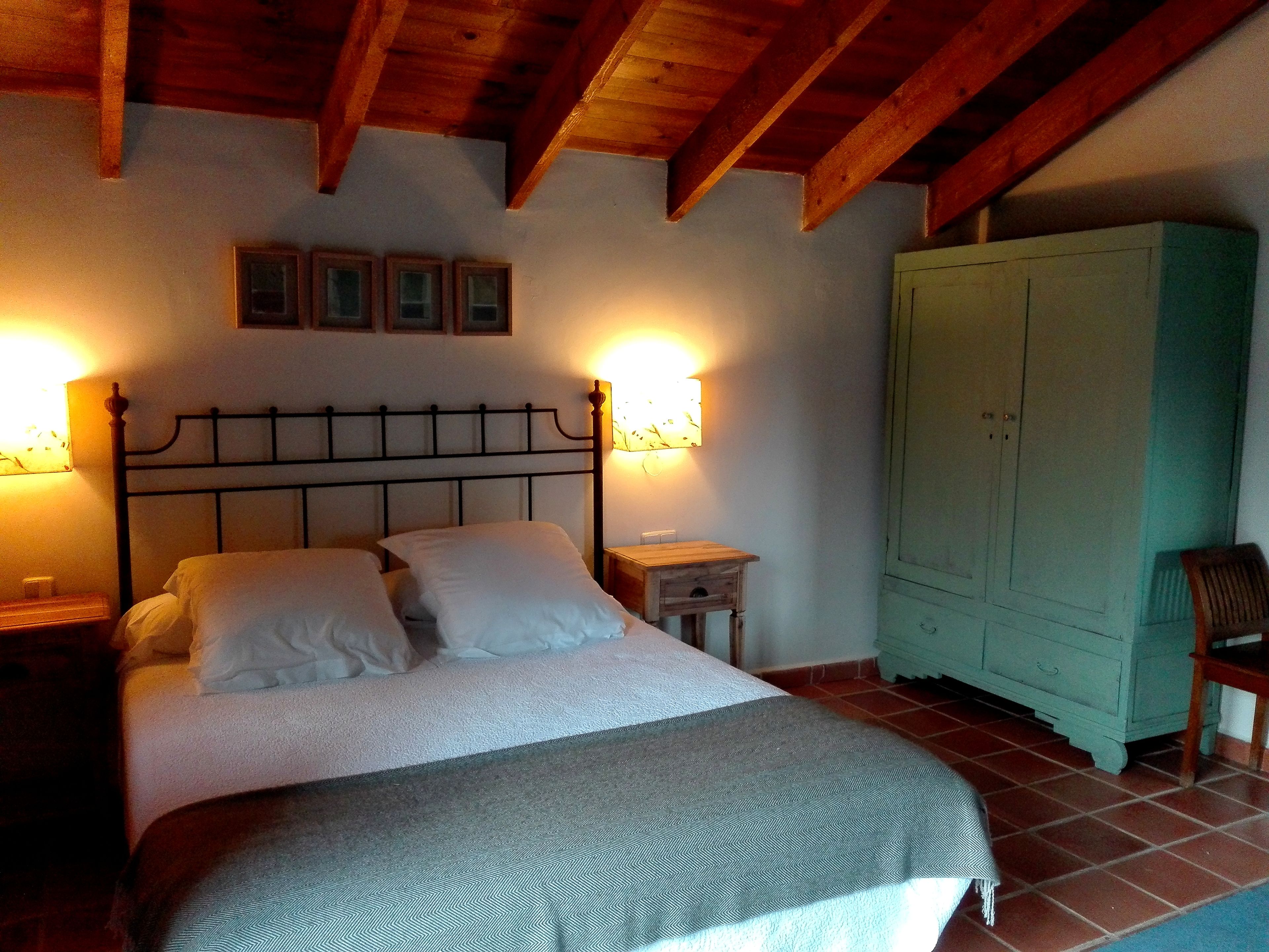A bedroom with a bed, bedside lamps, a wardrobe, and a small table.