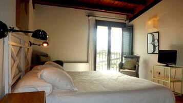 Un dormitorio con una cama grande, un escritorio, una silla, un televisor y un balcón con vistas.