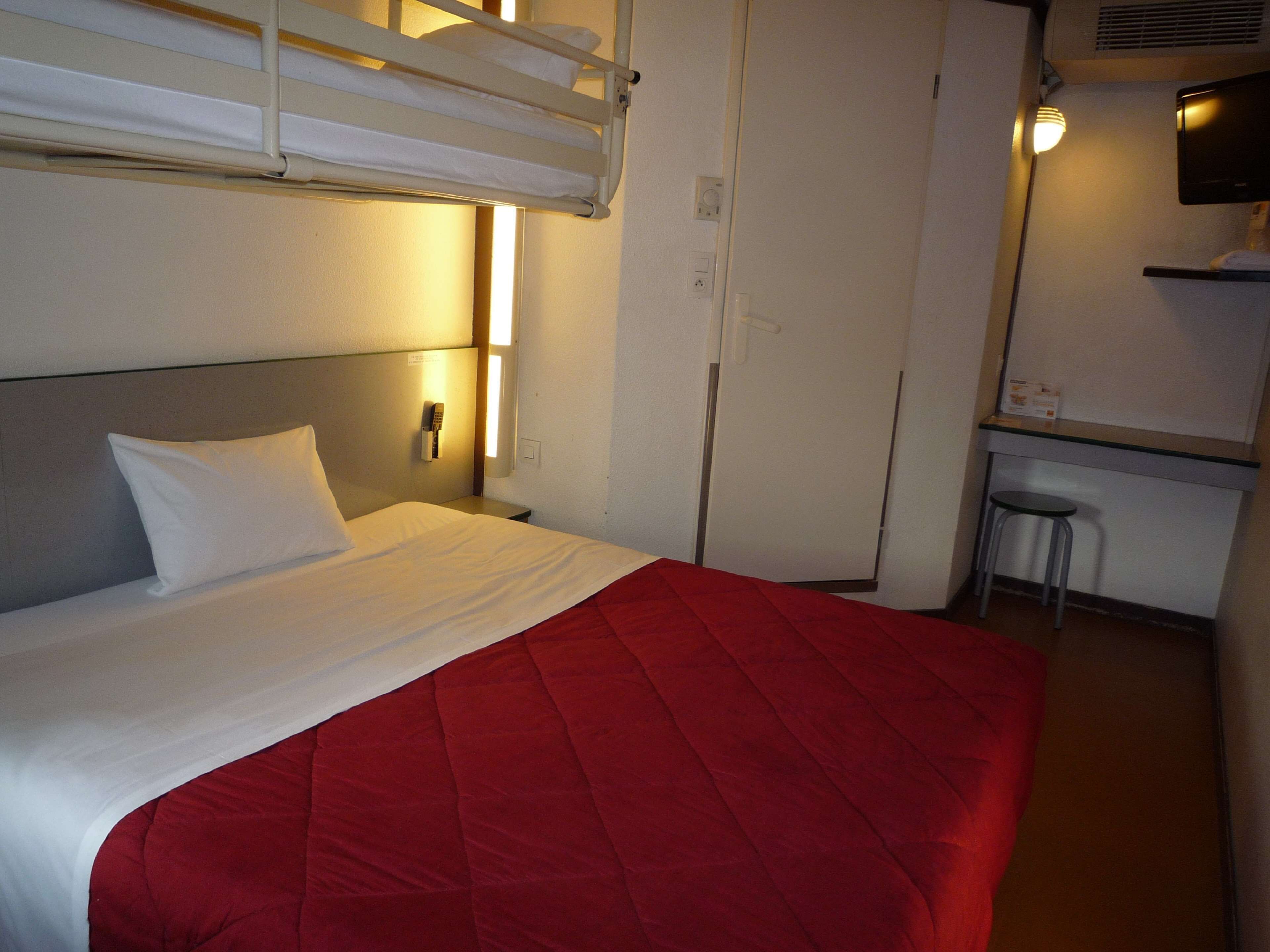 A hotel room with a bed, a desk, and a chair.