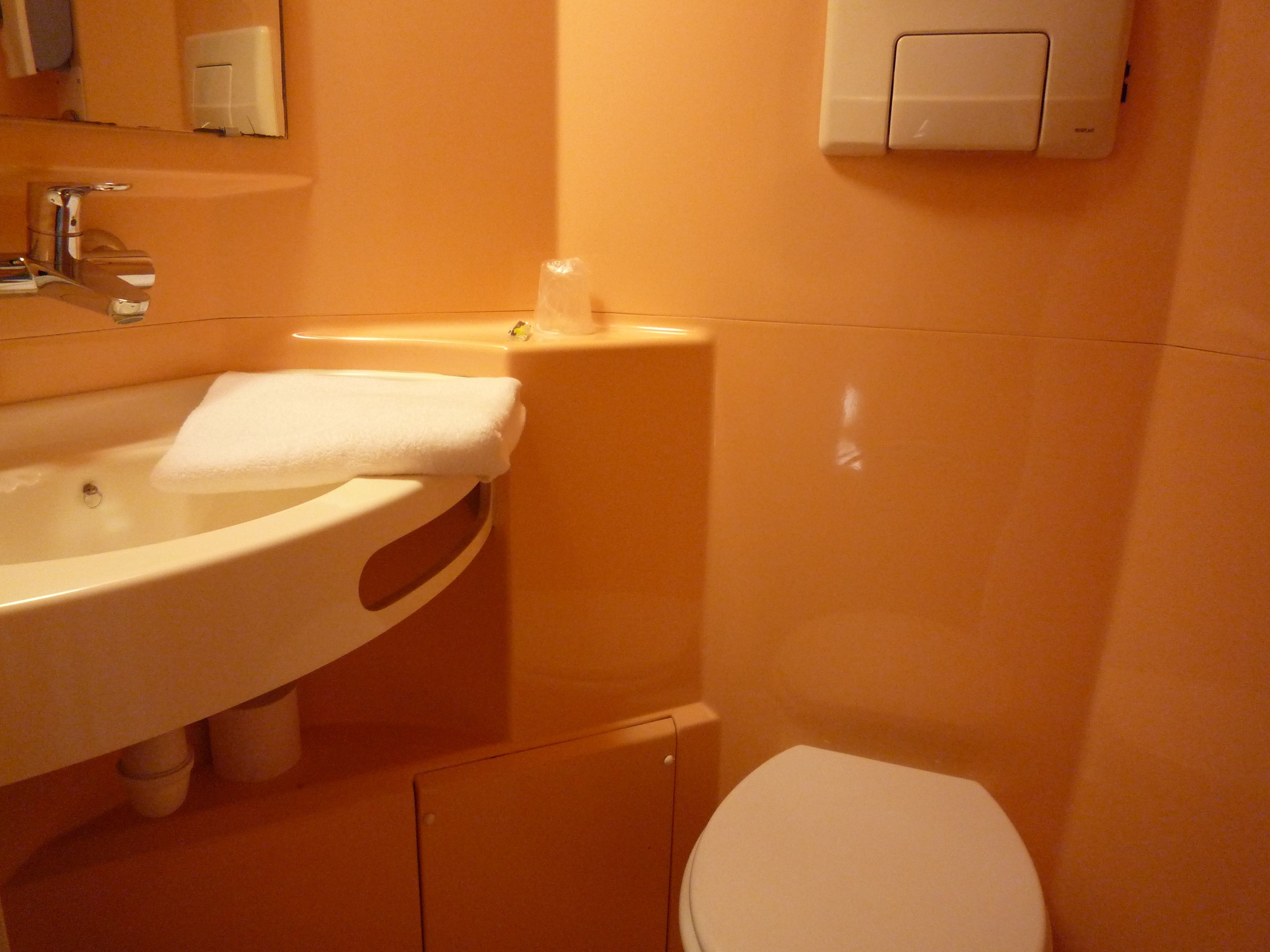 Un baño con lavamanos, espejo e inodoro.