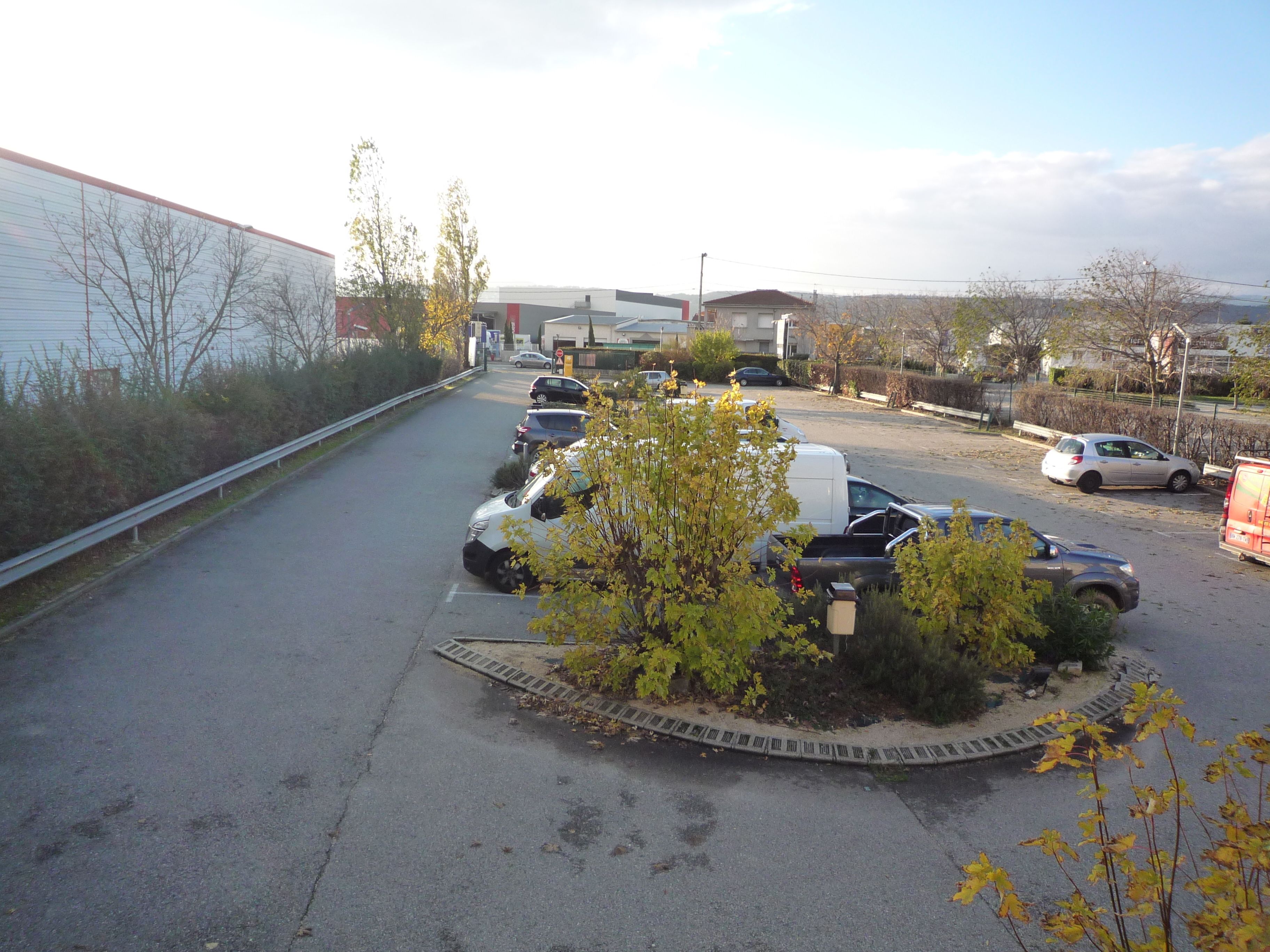 A parking lot with several cars and a white building in the background.