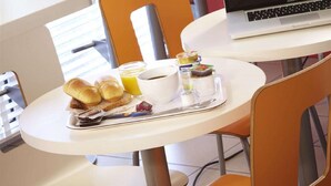 A breakfast tray with a sandwich, juice, and a cup of coffee on a white table. - Première Classe Valence Sud (Valence)