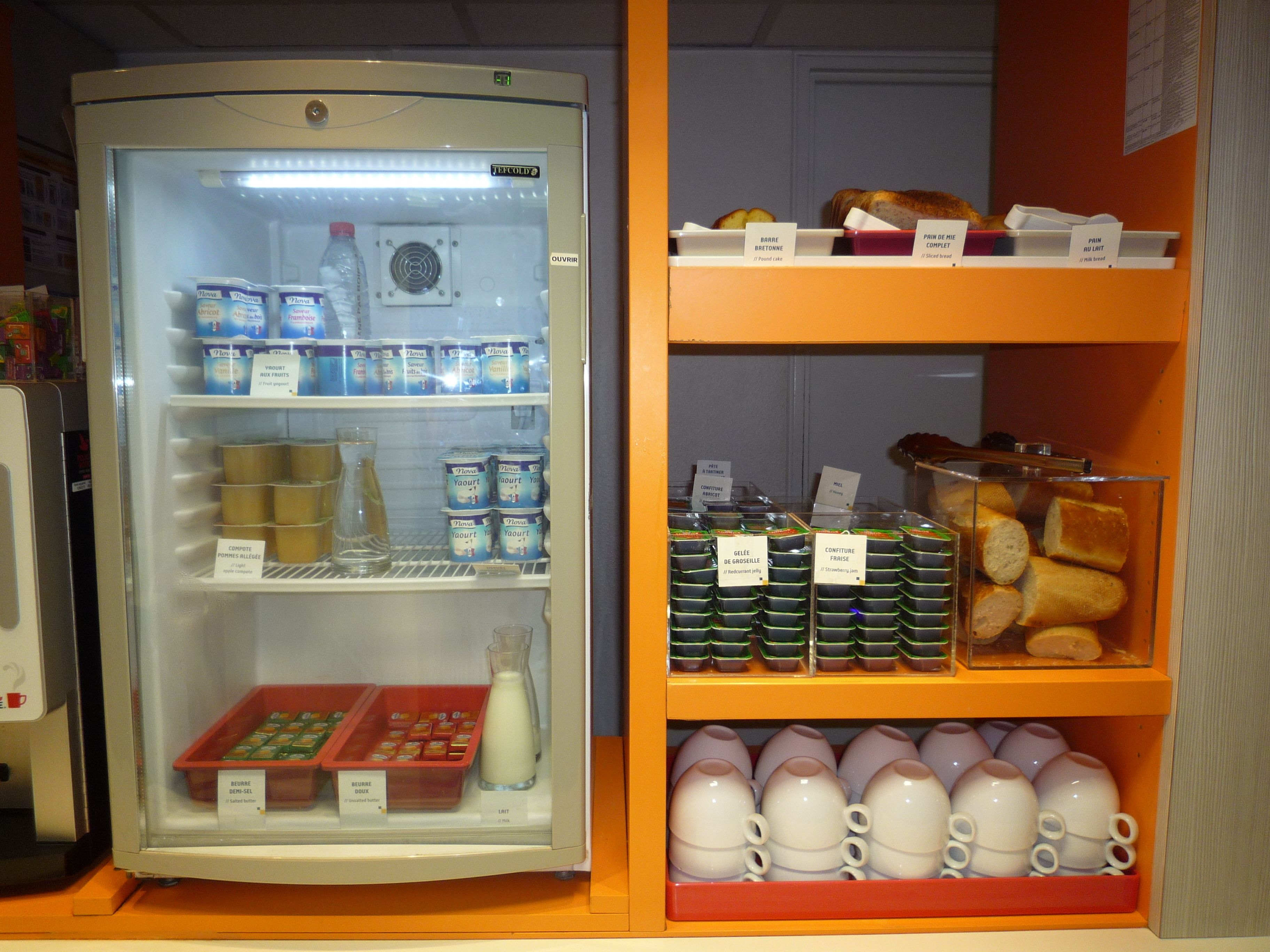Un refrigerador lleno de productos lácteos variados y una repisa con pan y pasteles.