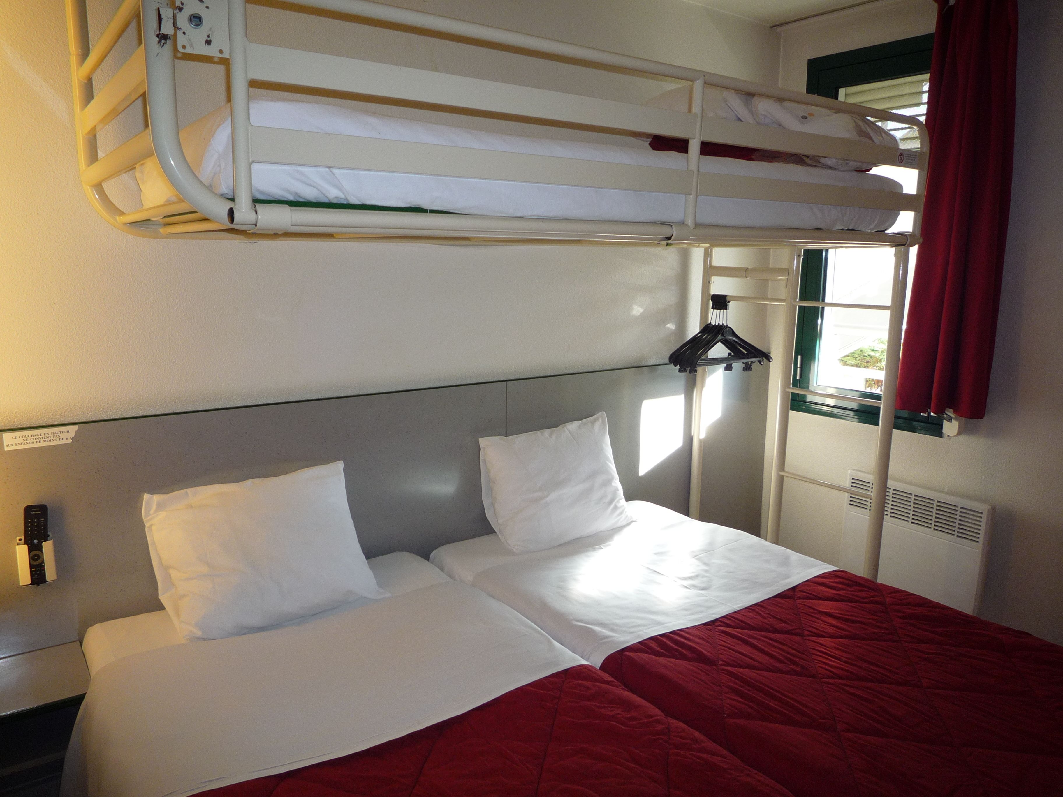 A bunk bed with two white pillows and a red blanket.