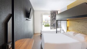 Een hotelkamer met twee bedden, een houten bureau, een flatscreen televisie en een raam met gordijnen.