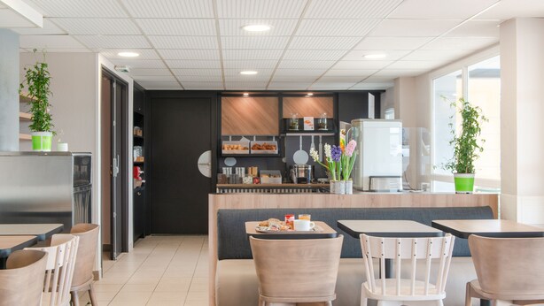 Een modern café met zitplaatsen, een toonbank en een koelkast.