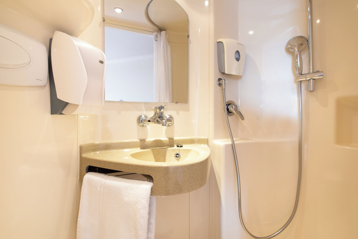 A modern bathroom with a sink, mirror, and shower.