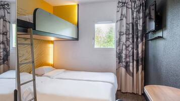 Quarto com beliches, uma escrivaninha, televisão e janela com cortinas.