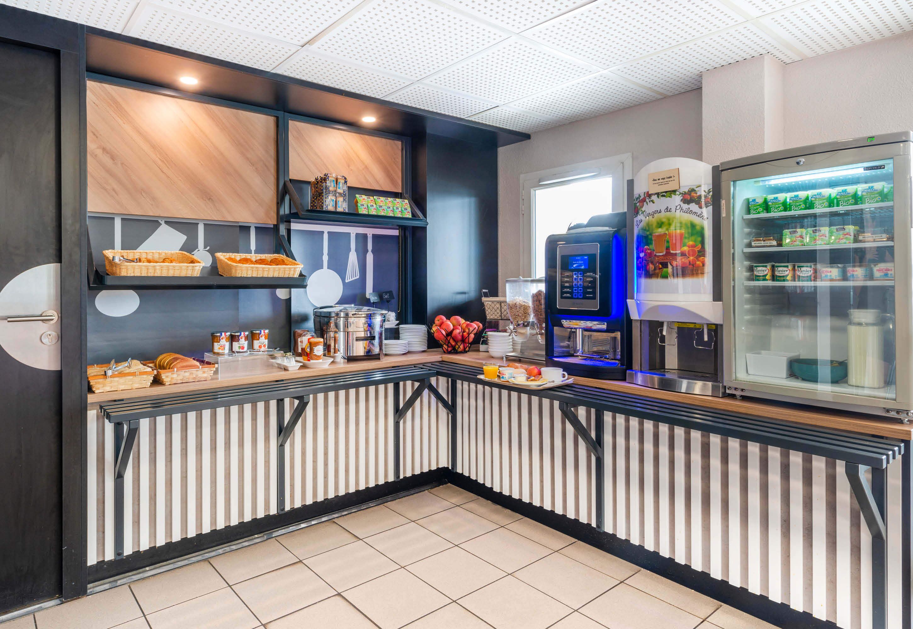Una barra de desayuno moderna con una máquina de café, un refrigerador lleno de bebidas y una variedad de alimentos para el desayuno.