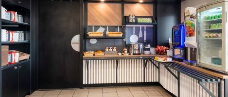 Una cocina moderna con mostrador, estanterías con libros, un refrigerador y una cafetera.