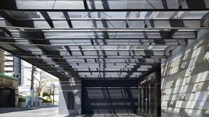 An urban pedestrian walkway with a modern architectural design, featuring a metal roof structure and stone walls. - Hotel Park Side Hiroshima Peace Park (Hiroshima)