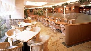 Un restaurante con mobiliario de mimbre, suelo de piedra y vistas al exterior.