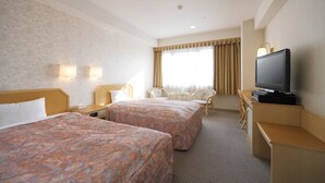 Habitación de hotel con dos camas, televisión, escritorio y una silla.