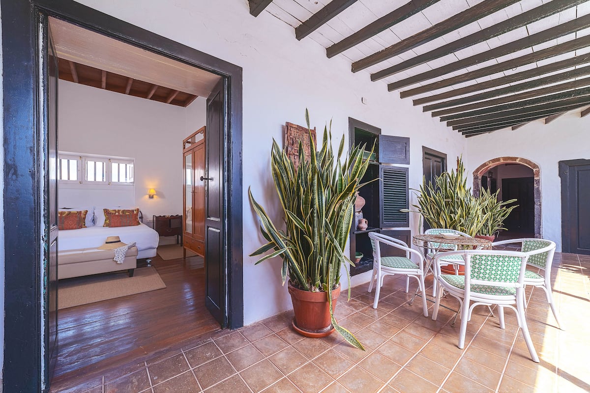 Une pièce avec un lit, une plante en pot et une table avec des chaises.