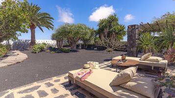 Relax in a serene outdoor lounge surrounded by lush tropical plants and palm trees.