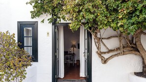 Un bâtiment blanc avec une porte sombre et une petite table sur laquelle se trouve une lampe.
