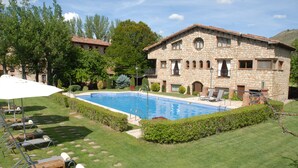A stone building with a swimming pool, surrounded by a well-maintained lawn and trees. - Hotel-SPA El Molino de Alcuneza (Siguenza)