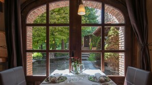 A table set for two with a view of a brick garden through a large arched window. - Hotel-SPA El Molino de Alcuneza (Siguenza)