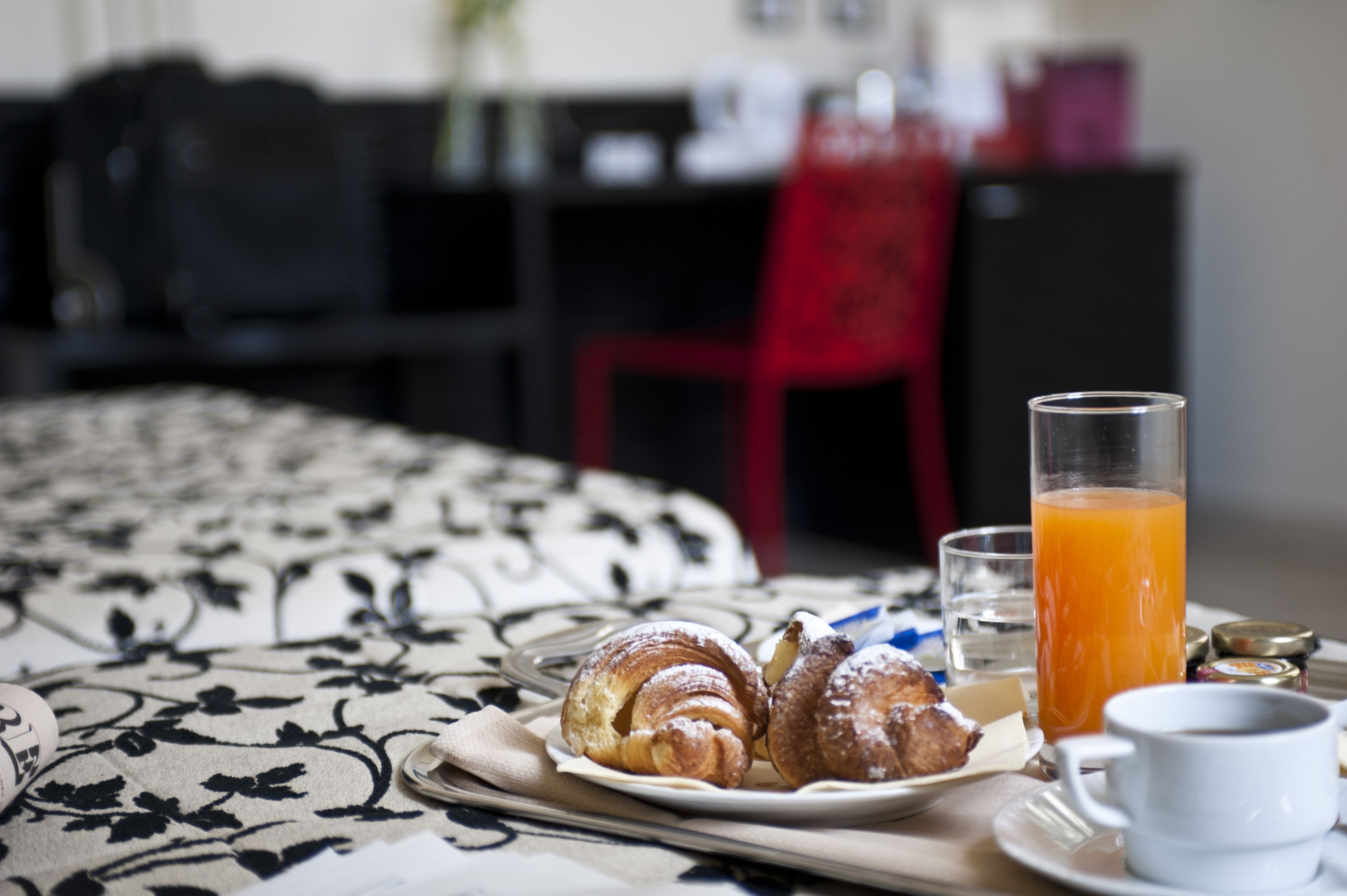 Desayuno con cruasanes, un vaso de jugo de naranja y una taza sobre una cama.