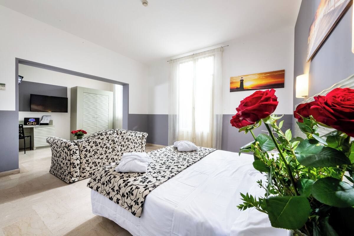 Une chambre d’hôtel avec un lit, un bureau, une télévision et un tableau au mur.