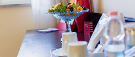 A dining table with a fruit bowl, cups, and a water bottle.