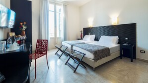 Une chambre d’hôtel moderne, équipée d’un lit, de tables de chevet, d’un bureau avec une chaise, d’une télévision et d’une fenêtre avec des rideaux.
