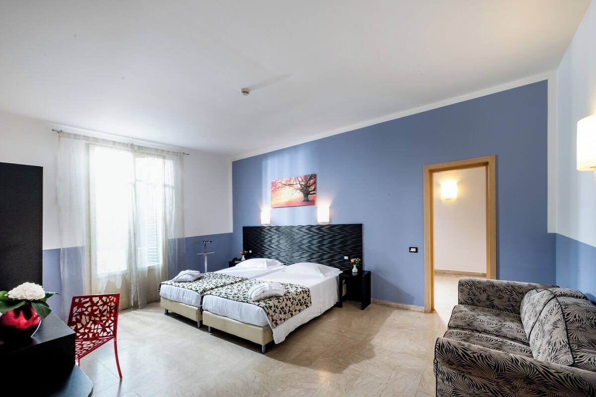 Une chambre à coucher avec un lit, une table de chevet, une chaise et un tableau au mur.