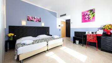 A modern hotel room with a large bed, a desk, and two wall-mounted lamps.