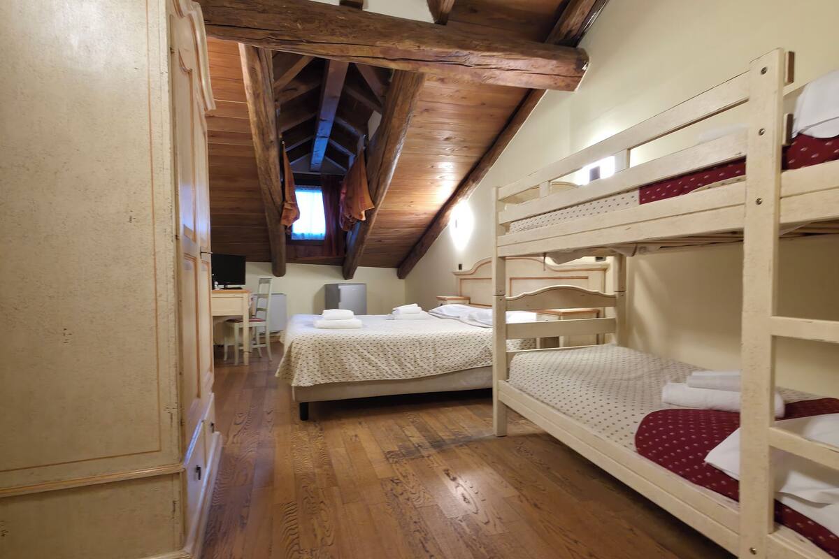 Ein Zimmer mit Holzboden, Etagenbetten, einem Kleiderschrank und einem Schreibtisch mit Stuhl.