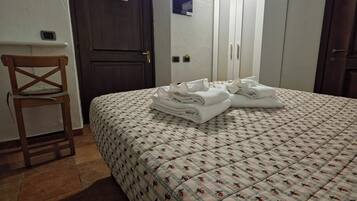 Ein Schlafzimmer mit einem Bett, einem Holzstuhl, einem Kleiderschrank und einer Tür.