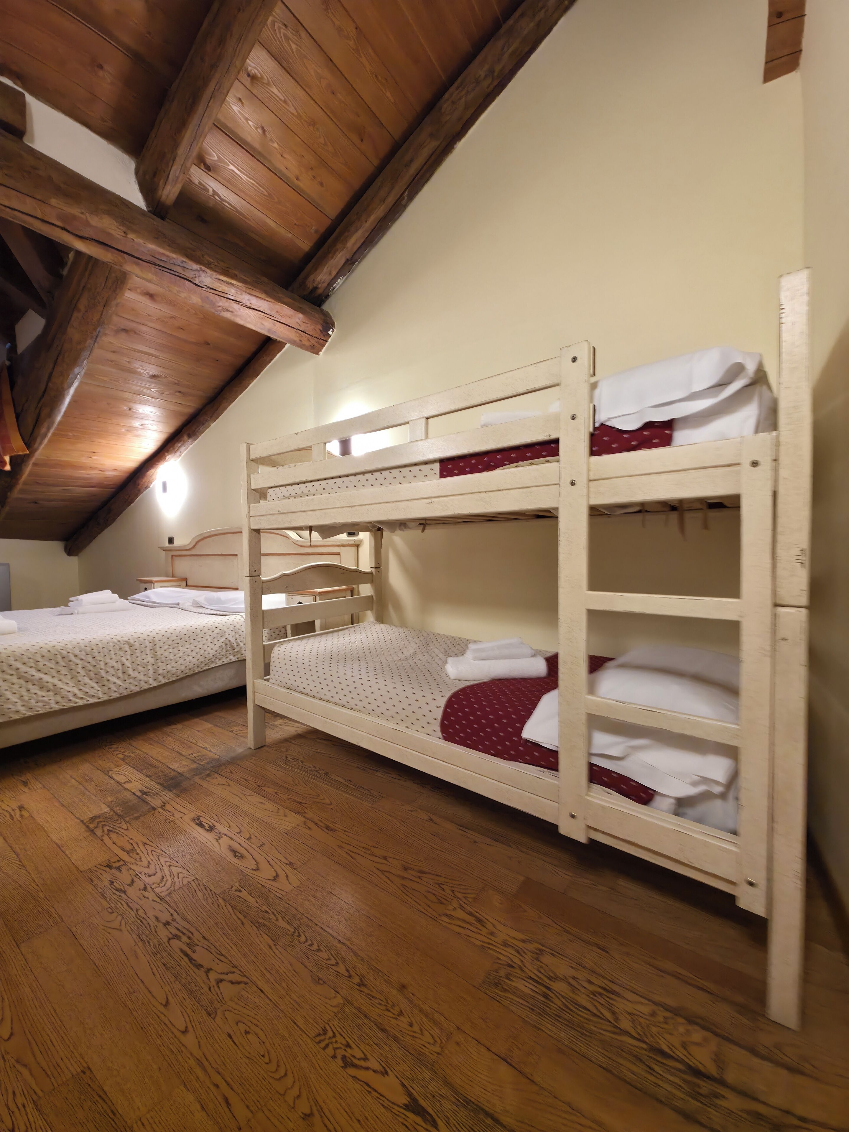 Ein Zimmer mit zwei Etagenbetten, Holzboden und einer schrägen Decke.