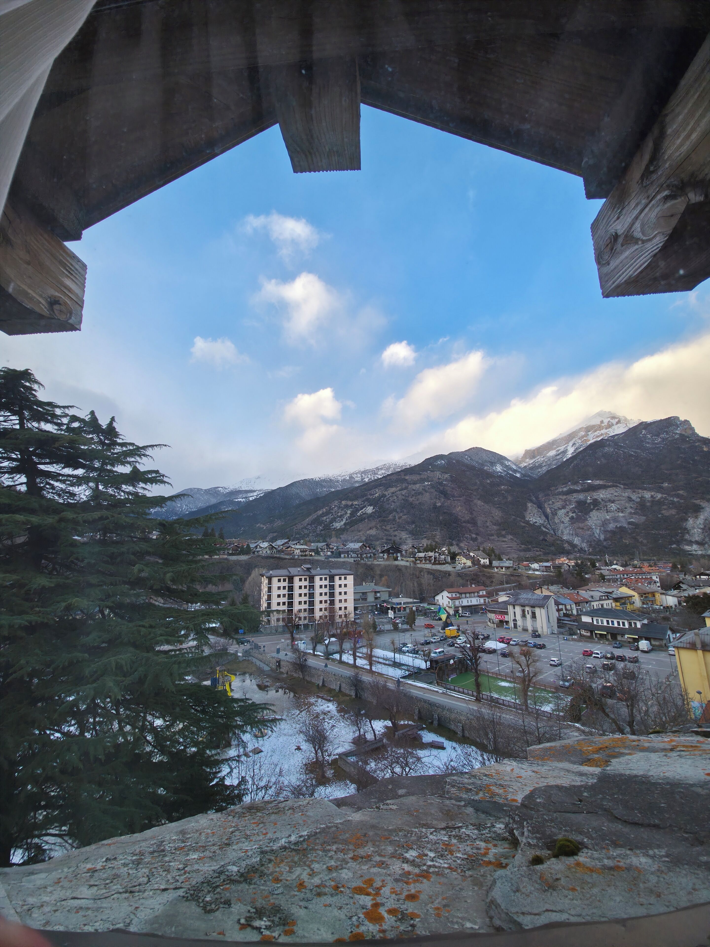 A view through a concrete structure with a town, buildings, and mountains in the background.