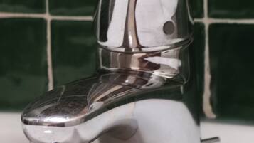 A chrome faucet with a single handle on a white sink.