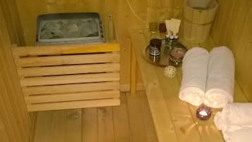 Un sauna de madera con bancos, toallas, un lavabo y un recipiente con hielo.