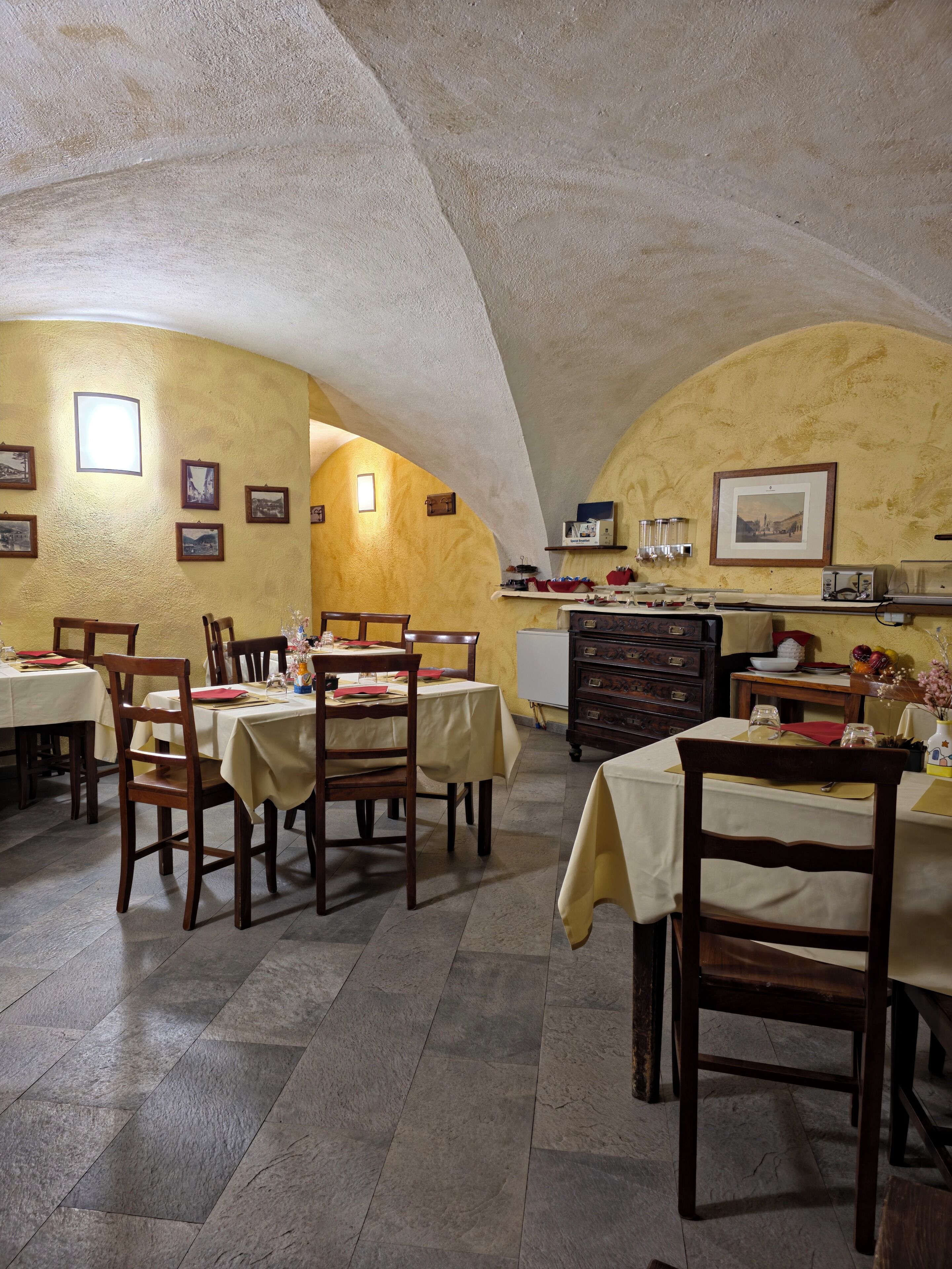 A dining area with tables and chairs, a kitchen area with appliances, and a vaulted ceiling.