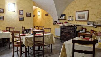 A dining area with tables and chairs, a kitchen area with appliances, and a vaulted ceiling.