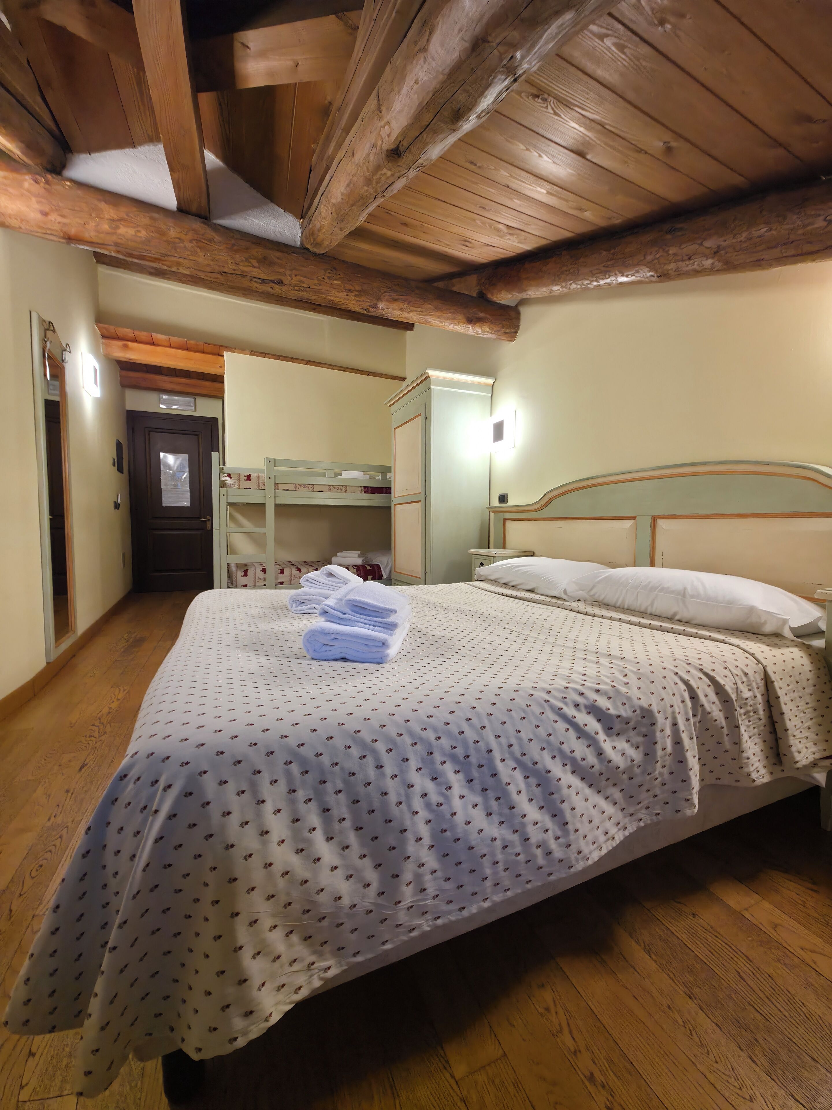 Ein Schlafzimmer mit Bett, Holzboden, einer Tür und einem kleinen Tisch mit Handtüchern.