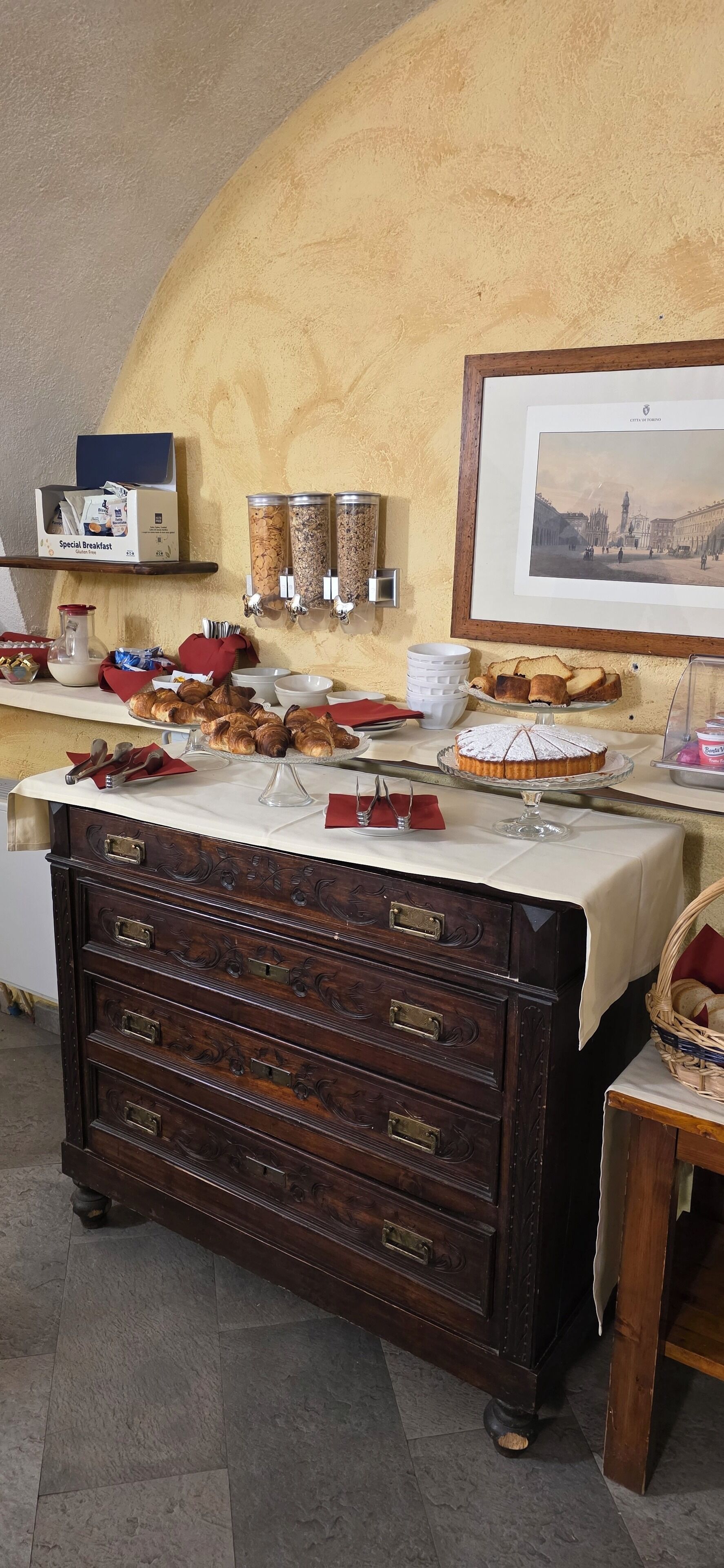 Een ontbijtbuffet met gebak, een koffiehoek en een lijstmuur.