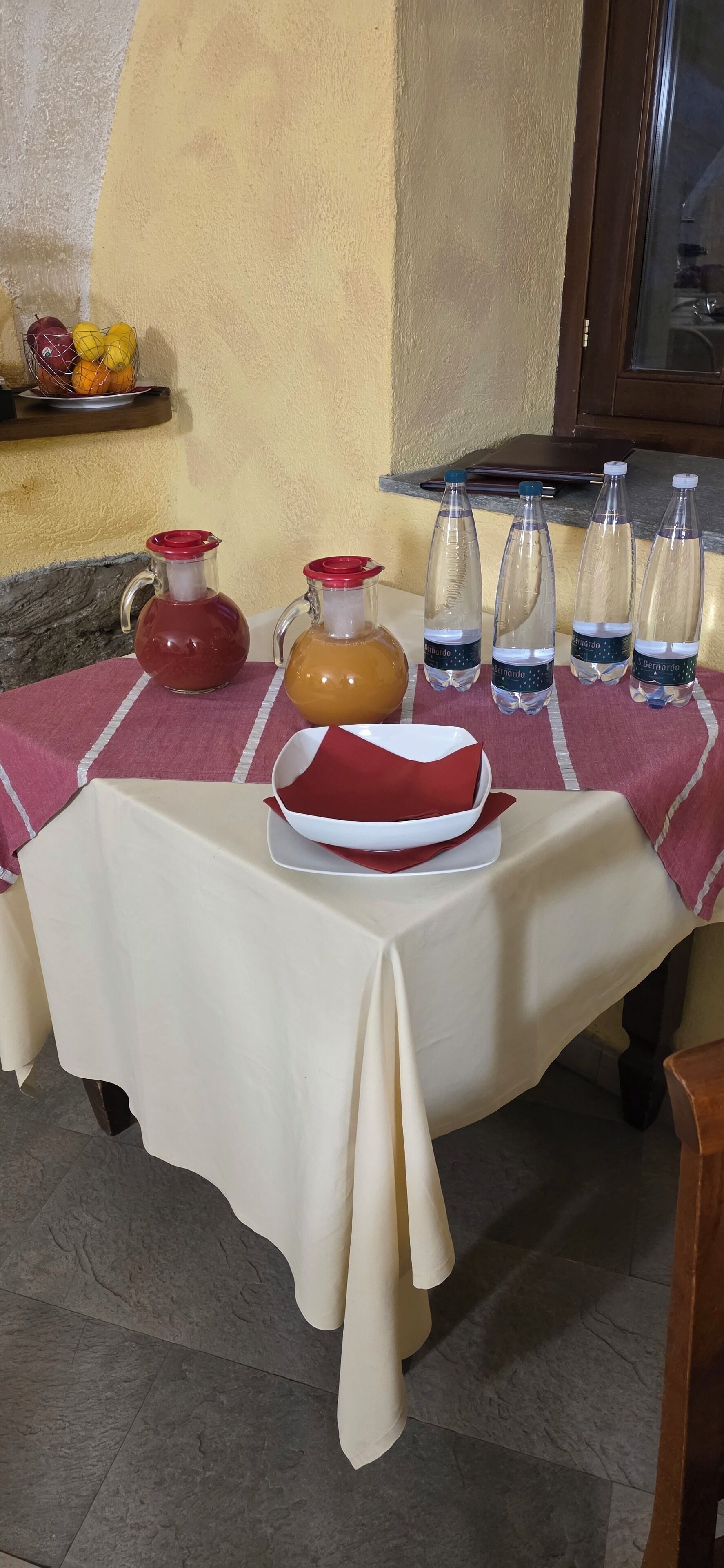 A table set with a red and white tablecloth, a pitcher, a jug, a plate, and several water bottles.