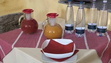 A table set with a red and white tablecloth, a pitcher, a jug, a plate, and several water bottles.