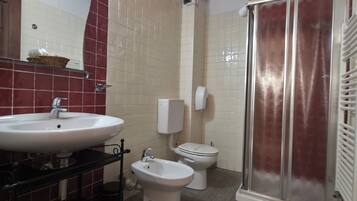 A bathroom with a sink, bidet, toilet, and shower.