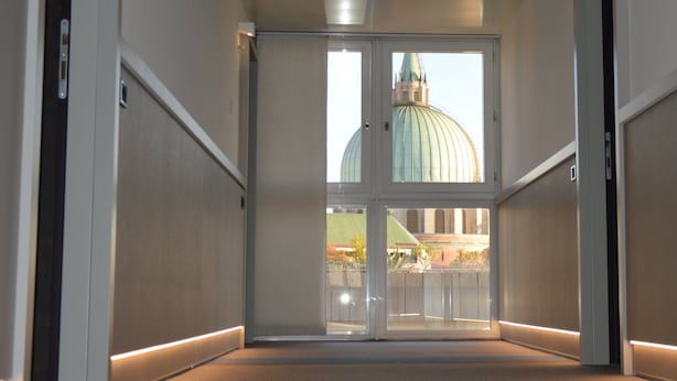 A corridor with a glass door leading to a view of a large dome structure.