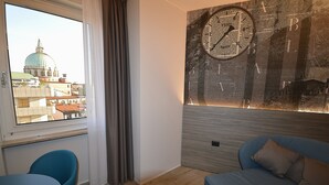 A room with a view of a dome building, a wall clock, a blue sofa, and a small table.