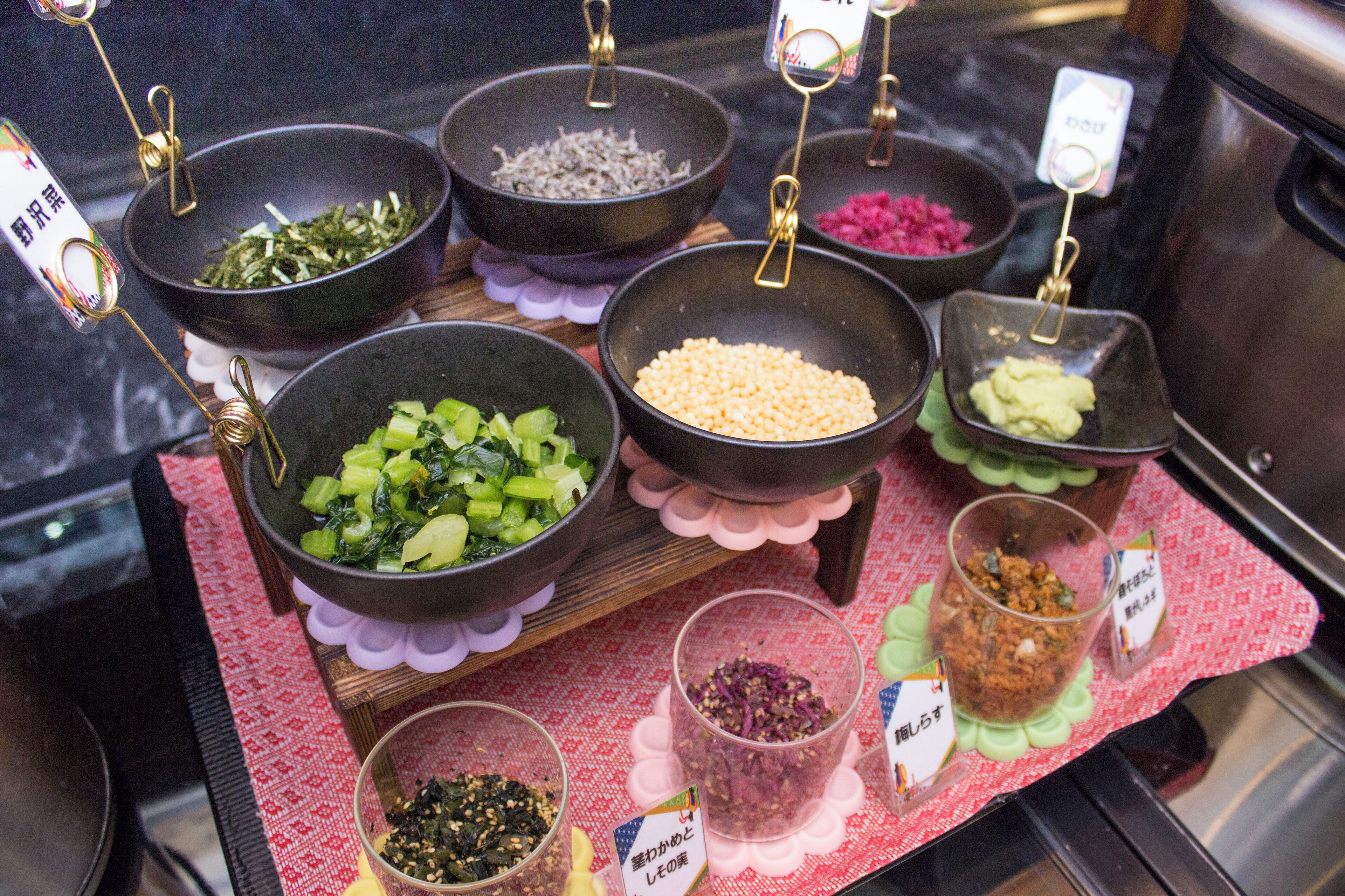 A variety of food items displayed in bowls and glasses on a table with a red patterned tablecloth.