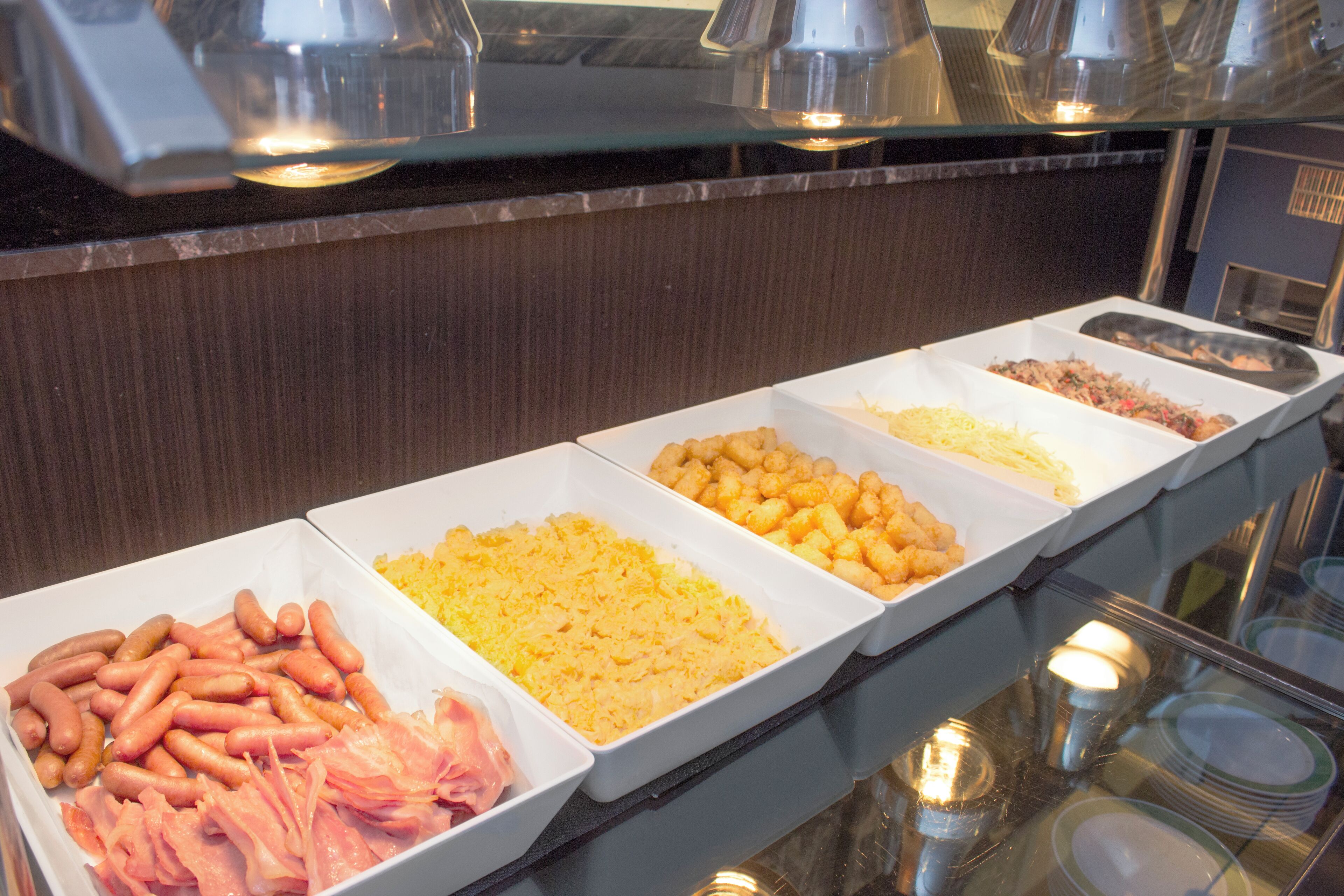 A buffet with various food items including sausages, cheese, and other prepared dishes.
