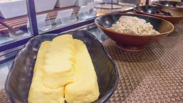 Una mesa con un posavasos tejido, un cuenco negro con comida amarilla y un cuenco marrón con comida blanca.
