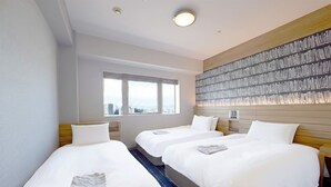 Habitación de hotel con tres camas, un ventanal grande y un panel decorativo en la pared.